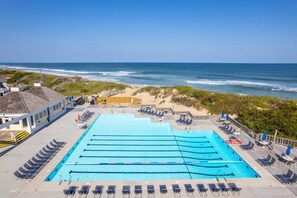 Ein Schwimmbecken mit mehreren Bahnen, Blick auf den Strand und Liegestühle.