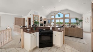 A spacious kitchen with a large island, a dining area with a sofa, and a view of the ocean. - Mermaids Pearl: Sound Views, Village Beach Club and YMCA Access, Hot Tub (Nags Head)