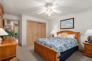 A bedroom with a wooden bed, a ceiling fan, a nightstand, a dresser, and a framed picture on the wall. - Mermaids Pearl: Sound Views, Village Beach Club and YMCA Access, Hot Tub (Nags Head)