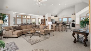 A spacious living room with a sectional sofa, a coffee table, and a dining area with a bar. - Mermaids Pearl: Sound Views, Village Beach Club and YMCA Access, Hot Tub (Nags Head)