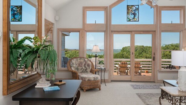 A spacious room with large windows, a ceiling fan, and a view of the outdoors. - Mermaids Pearl: Sound Views, Village Beach Club and YMCA Access, Hot Tub (Nags Head)