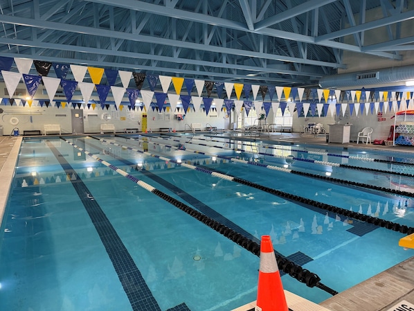 An indoor swimming pool with multiple lanes, overhead beams, and safety equipment. - Mermaids Pearl: Sound Views, Village Beach Club and YMCA Access, Hot Tub (Nags Head)