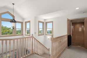 A spacious hallway with a wooden railing, large windows, and a view of the outdoors. - Mermaids Pearl: Sound Views, Village Beach Club and YMCA Access, Hot Tub (Nags Head)