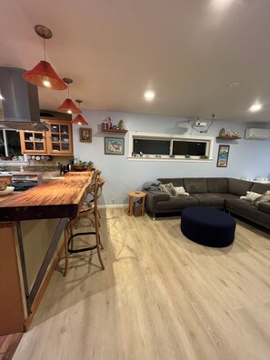 Una cocina moderna con barra, un sofá gris y un otoman redondos.