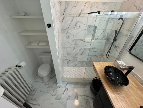 A bathroom with a toilet, shower, and a sink with a black basin.