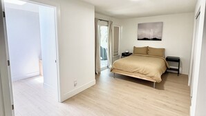 A spacious bedroom with a large bed, a nightstand, and a window with curtains. - Fully Remodeled Spacious 4BD/2BTH Oasis Full of Amenities for Large Groups (Vallejo)