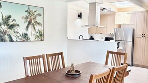 A dining area with a wooden table and chairs, a kitchen in the background, and a ceiling with skylights. - Fully Remodeled Spacious 4BD/2BTH Oasis Full of Amenities for Large Groups (Vallejo)