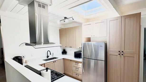 A modern kitchen with a central island, stainless steel appliances, and wooden cabinets. - Fully Remodeled Spacious 4BD/2BTH Oasis Full of Amenities for Large Groups (Vallejo)