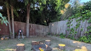 A backyard with a fire pit, wooden stump seating, a target on a tripod, and a wooden fence. - Fully Remodeled Spacious 4BD/2BTH Oasis Full of Amenities for Large Groups (Vallejo)