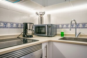 Una cucina con microonde, macchina del caffè e lavandino.