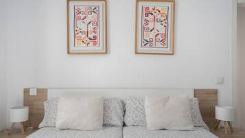 Una cama doble con colcha de estampado floral, dos almohadas blancas y un cabecero de madera.