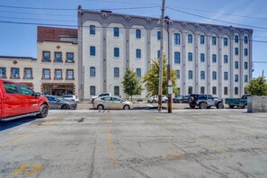 Ein Parkplatz mit mehreren Autos, ein Gebäude mit vielen Fenstern und ein Baum im Vordergrund.