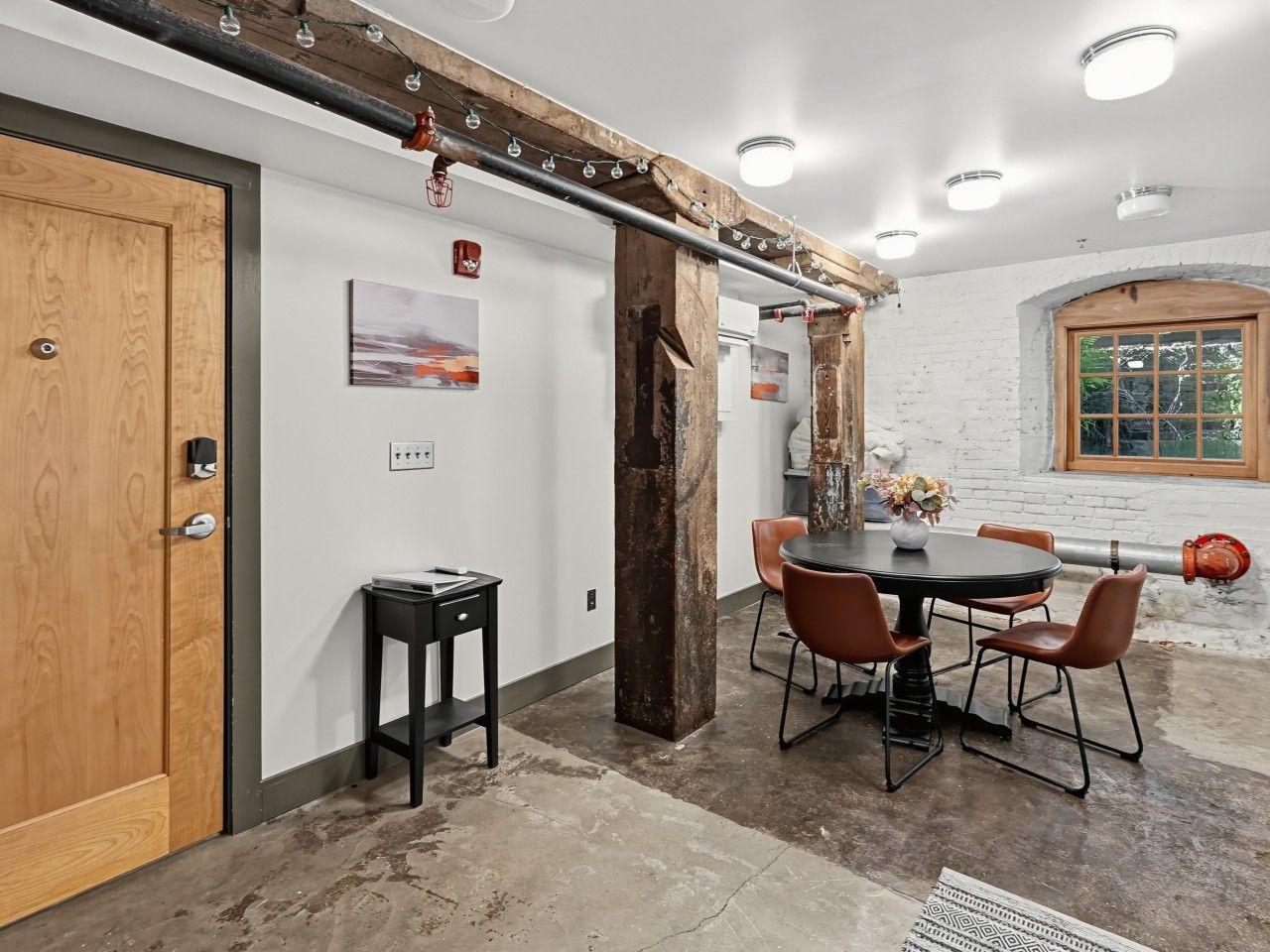 Une pièce avec une porte en bois, une table avec des chaises et une fenêtre donnant sur un paysage agréable.