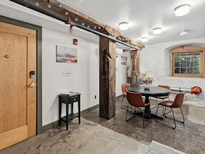 A room with a wooden door, a table with chairs, and a window with a view.