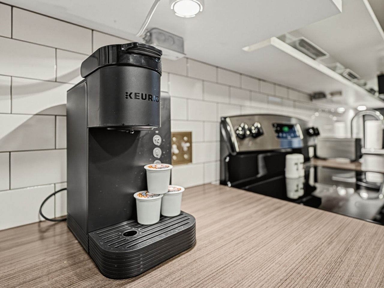 Une machine à café moderne dotée d’un panneau de commande et de deux tasses sur son socle.