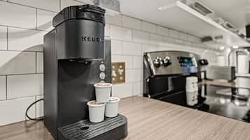 Une machine à café moderne dotée d’un panneau de commande et de deux tasses sur son socle.