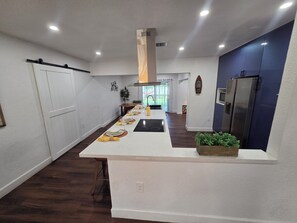 A modern kitchen with a central island, white cabinetry, and a stainless steel refrigerator.