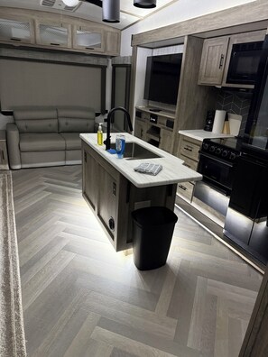 Una cocina moderna con una isla central, electrodomésticos integrados y un suelo con estampado de espiga.