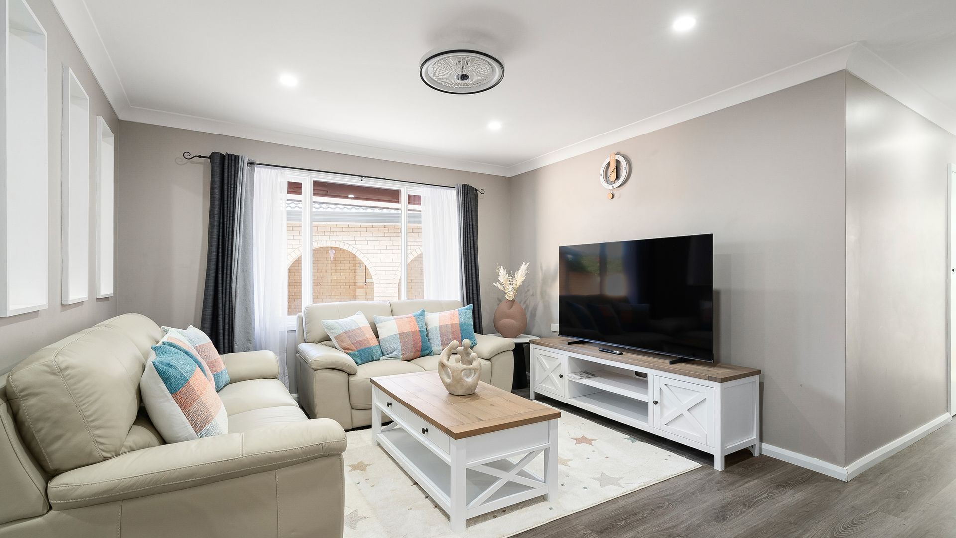 A modern living room with a sofa, coffee table, TV stand, and a decorative vase.
