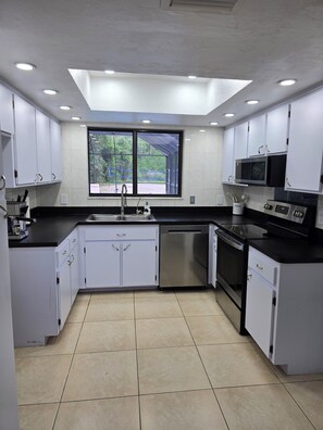 A modern kitchen with white cabinets, a stainless steel dishwasher, a microwave, and an oven. - 1 Acre Oasis · Pool, Billiards & Volleyball. Great location. (Naples)