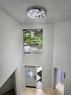 A modern interior with a large window, a door with an oval glass panel, and a chandelier. - 1 Acre Oasis · Pool, Billiards & Volleyball. Great location. (Naples)