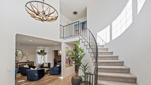 A spacious living area with a curved staircase and a large window. - OSide Private PoolHome 4bed/3Bth (Oceanside)