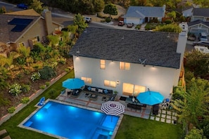Ein Wohnhaus mit Swimmingpool, Terrassenmöbeln und einem gepflegten Garten.