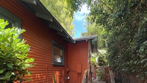 A red house with a wooden bench and a concrete pathway leading to a set of stairs.