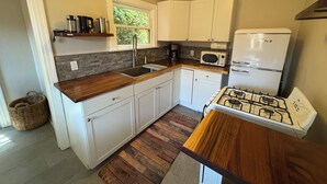 A compact kitchen with white cabinets, a gas stove, a microwave, and a coffee maker.