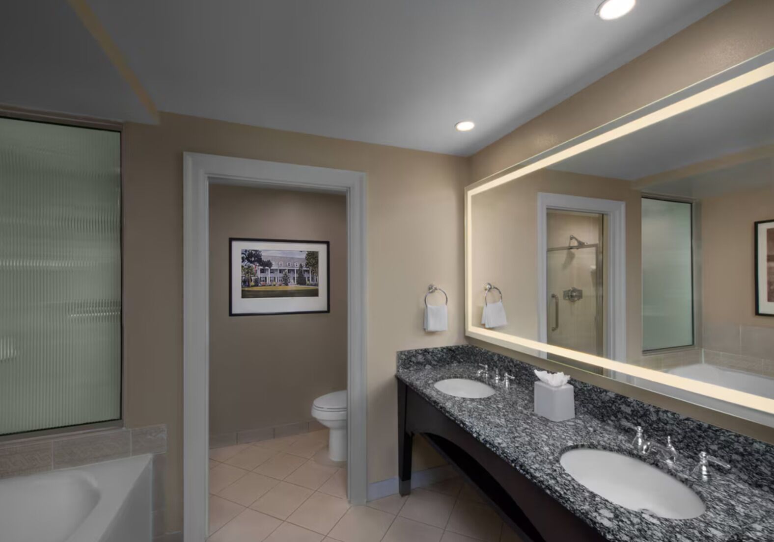 A modern bathroom with two sinks, a large mirror, and a framed picture on the wall.