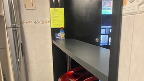 Kapea keittiö, jossa on jääkaappi, pesuallas ja baaritiski punaisilla jakkaroilla.