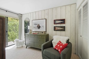 A room with a wooden paneled wall, a green sofa with a white fluffy pillow, a framed picture of a dog, and a small cabinet with a mirror. - Warm Springs Ranch Hideaway | Pool | Ski Access | Mtn. Views (Ketchum)