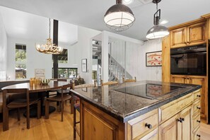 Eine moderne Küche mit Holzausstattung, einer Granit-Arbeitsplatte und Pendelleuchten.