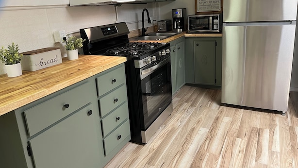 A kitchen with a gas stove, oven, microwave, and a stainless steel refrigerator. There are potted plants on the counter and a sign on the wall. - One bedroom apartment in the  finger lakes (Naples)
