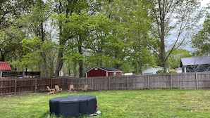 A backyard with a wooden fence, a red shed, and a black object on the grass. - One bedroom apartment in the  finger lakes (Naples)