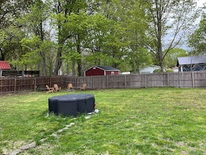 A backyard with a wooden fence, a red shed, and a black object on the grass. - One bedroom apartment finger lakes in lakes (Naples)