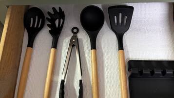 Uma gaveta com utensílios de cozinha, incluindo espátulas, pinças e um copo medidor.
