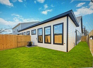 Ein modernes, zweistöckiges Haus mit großen Fenstern, einem eingezäunten Garten und einem gepflegten Rasen.