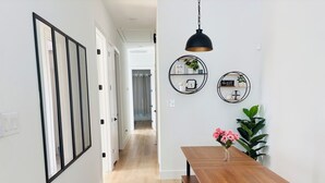 Un pasillo con una mesa de comedor de madera y bancos, una lámpara colgante y dos estantes de pared con adornos.