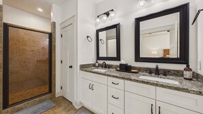 Un bagno con due lavandini, uno specchio grande e una zona doccia.