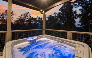 Un jacuzzi con vista a árboles y al atardecer.