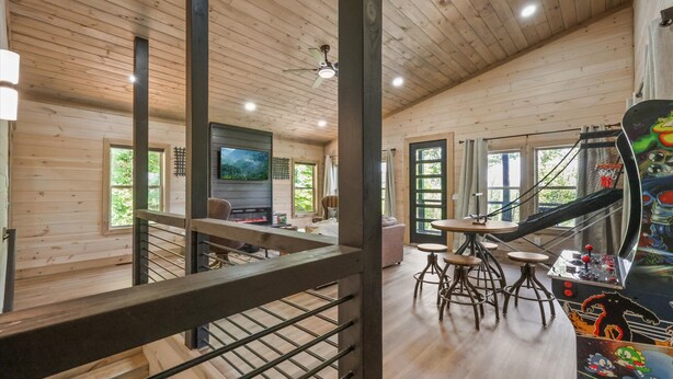 A wooden cabin interior with a dining area, bar, and arcade games. - Laurel House TN. Serenity, security & privacy. (Sevierville)