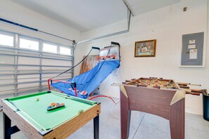 Une pièce équipée d’une table de billard, d’un baby-foot et d’un filet d’escalade bleu.