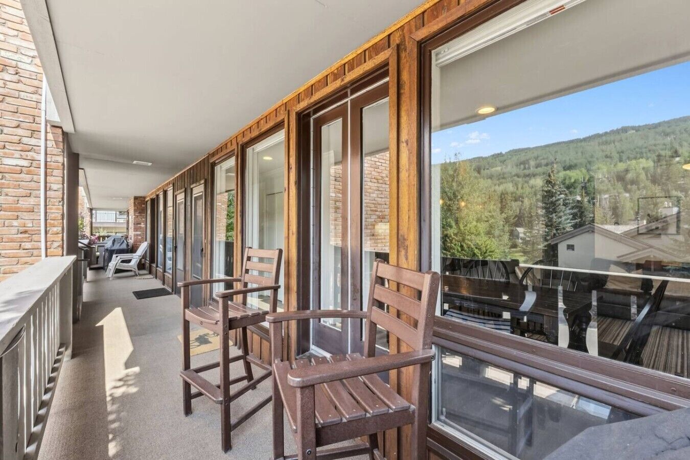 A balcony with wooden chairs and a view of a forested area.