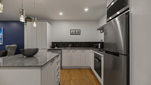 A modern kitchen with white cabinets, a stainless steel refrigerator, and a wooden floor. - Central Peaks Retreat - walk to CBD (Queenstown)