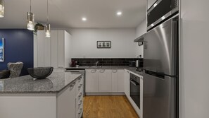Eine moderne Küche mit weißen Schränken, einem Edelstahlkühlschrank und Holzboden.