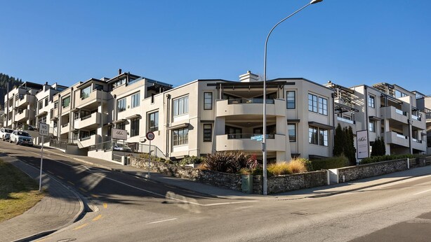 A multi-story residential building with balconies, a street sign indicating 'NO EXIT,' and a clear blue sky. - Central Peaks Retreat - walk to CBD (Queenstown)