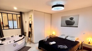 Ein modernes Schlafzimmer mit einem großen Bett, einer separaten Badewanne, einem Oberlicht und einem Bild an der Wand.