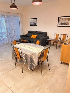 A living room with a sofa, a dining table with chairs, and a kitchen area. - Loft with Air Conditioning and Jacuzzi - Near Les Grands Buffets, Downtown (Narbonne)