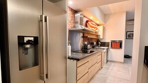 Eine moderne Küche mit einem Edelstahl-Kühlschrank, Holzschränken und einer Ziegelwand als Blickfang.